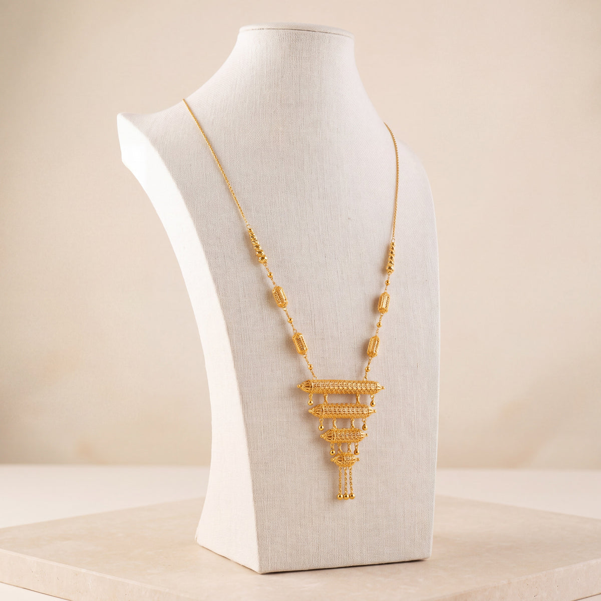 4 Step Mala Necklace 17 – Gold necklace with cylindrical beads, on travertine
