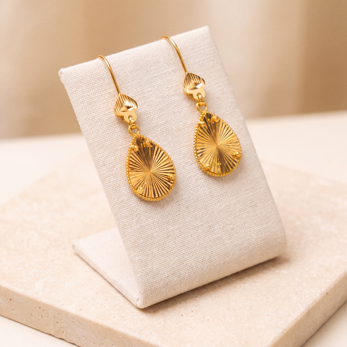 Drop Earrings – Gold teardrop earrings, on travertine