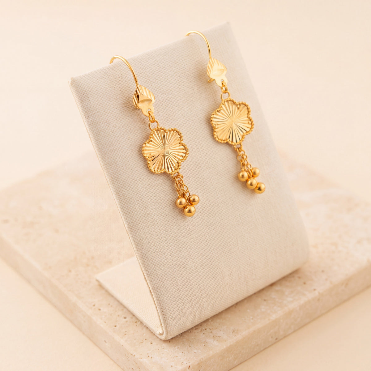 Flower Earrings 1 – Gold flower earrings with dangling beads, on travertine