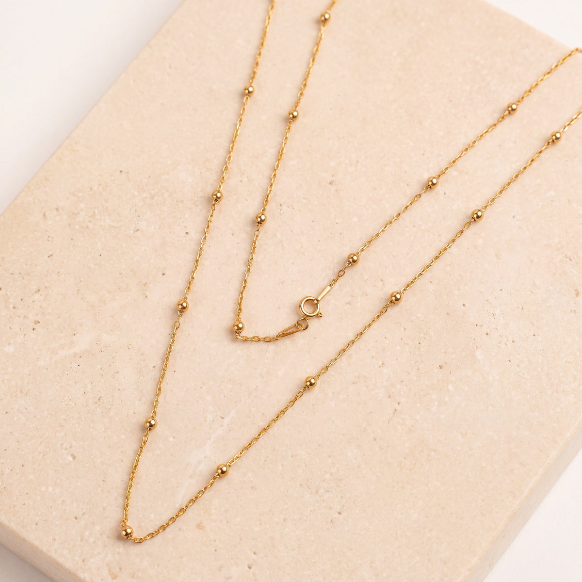 Link with Ball Chain 1 laid flat on travertine