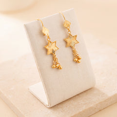 Star Earrings 1 – Gold star with chains, on travertine